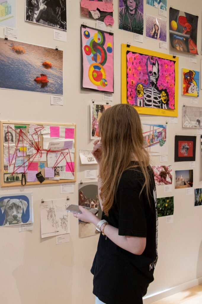 A young artist observing a salon style wall of paintings