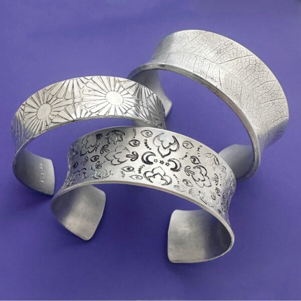 three metal cuffs with stamped patterns