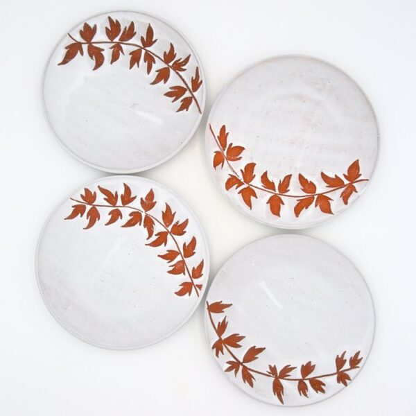 four white plates with trailing leaf pattern