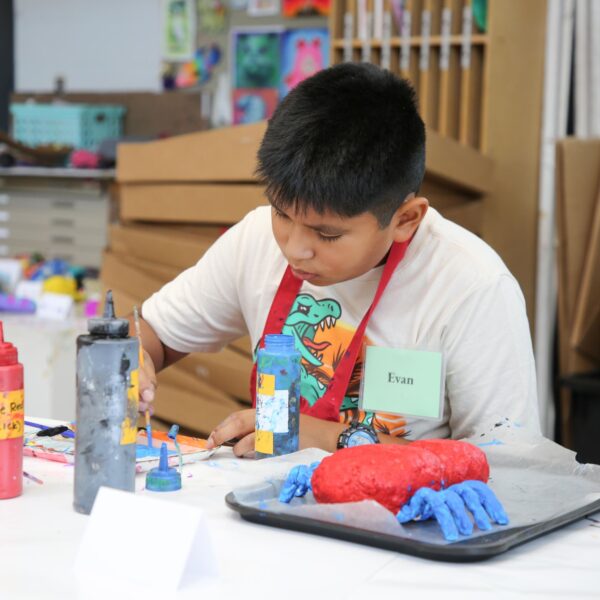 child painting a papier mache bug