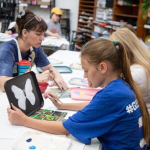 a child painting a butterfly on a black tray
