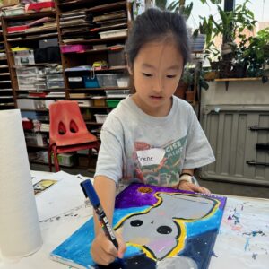a child drawing on a canvas with a paint marker