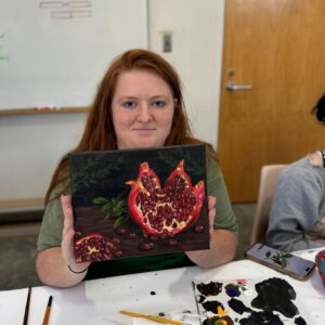 a teen holding a painting of pomegranate