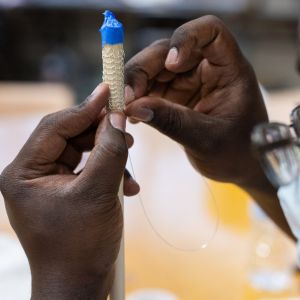 Close up image of an artist's hands weaving fine metal wire