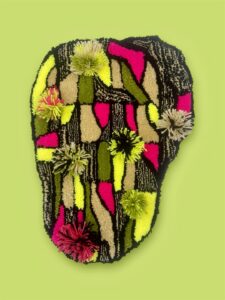 A small abstract rug in black, pink, and green with colorful tufts