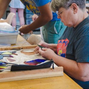 An artist applying copper foil to glass pieces