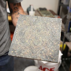 Resident Artist Jason Wang holding a tile decorated with a swirling pattern