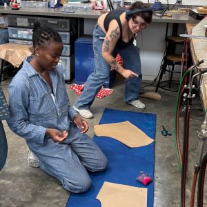 Two artists aligning pattern pieces on fabric.