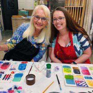 Two artists leaning together with watercolor test swatches