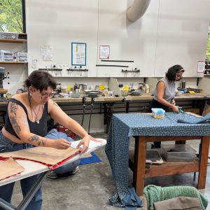 Two artists pinning and cutting fabric